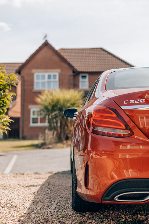 Red Car Parked on a Gravel Driveway