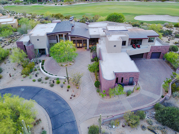 Mansion house with long driveway next to a green golf course