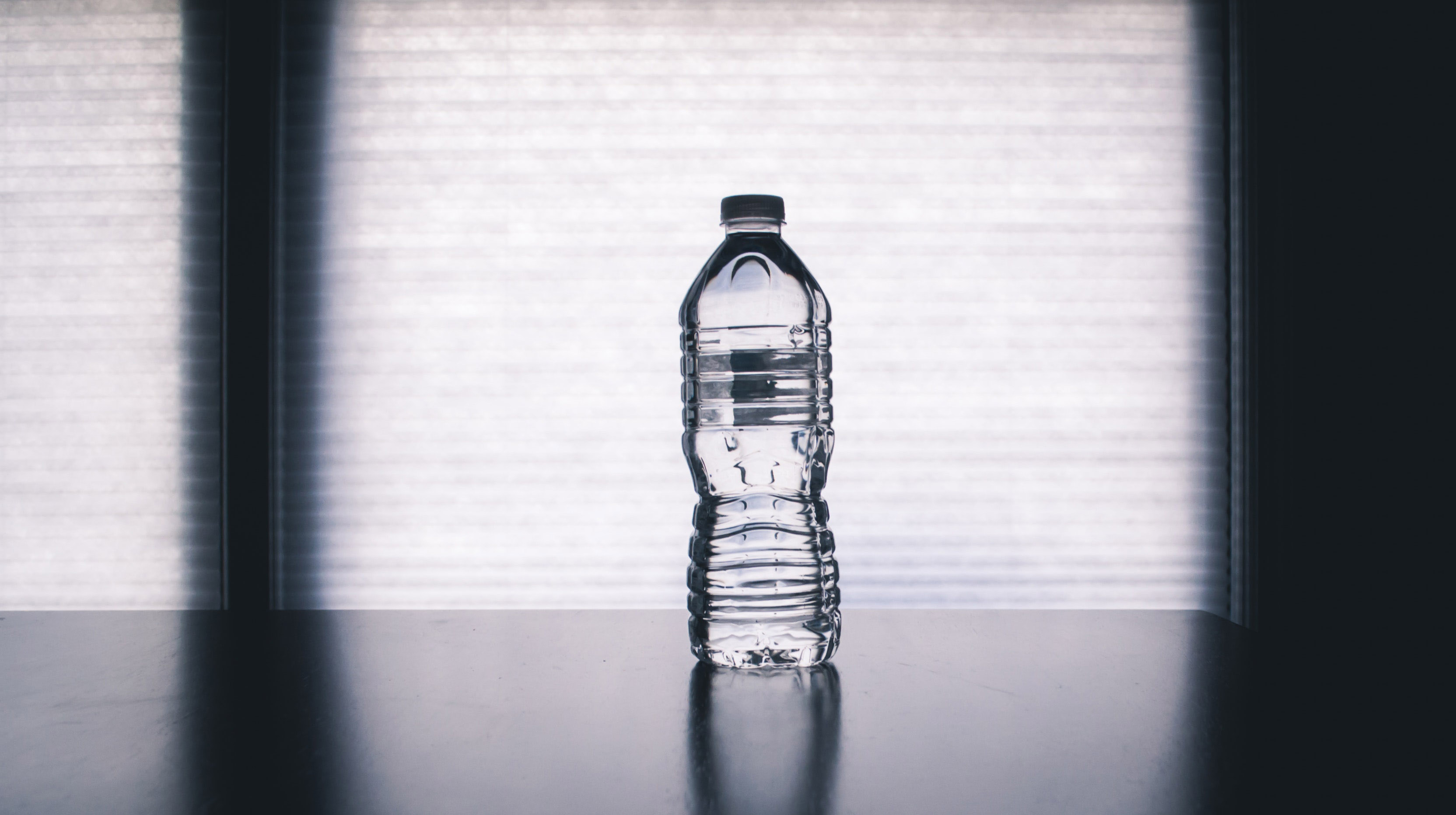 A clear plastic water bottle with a window behind it