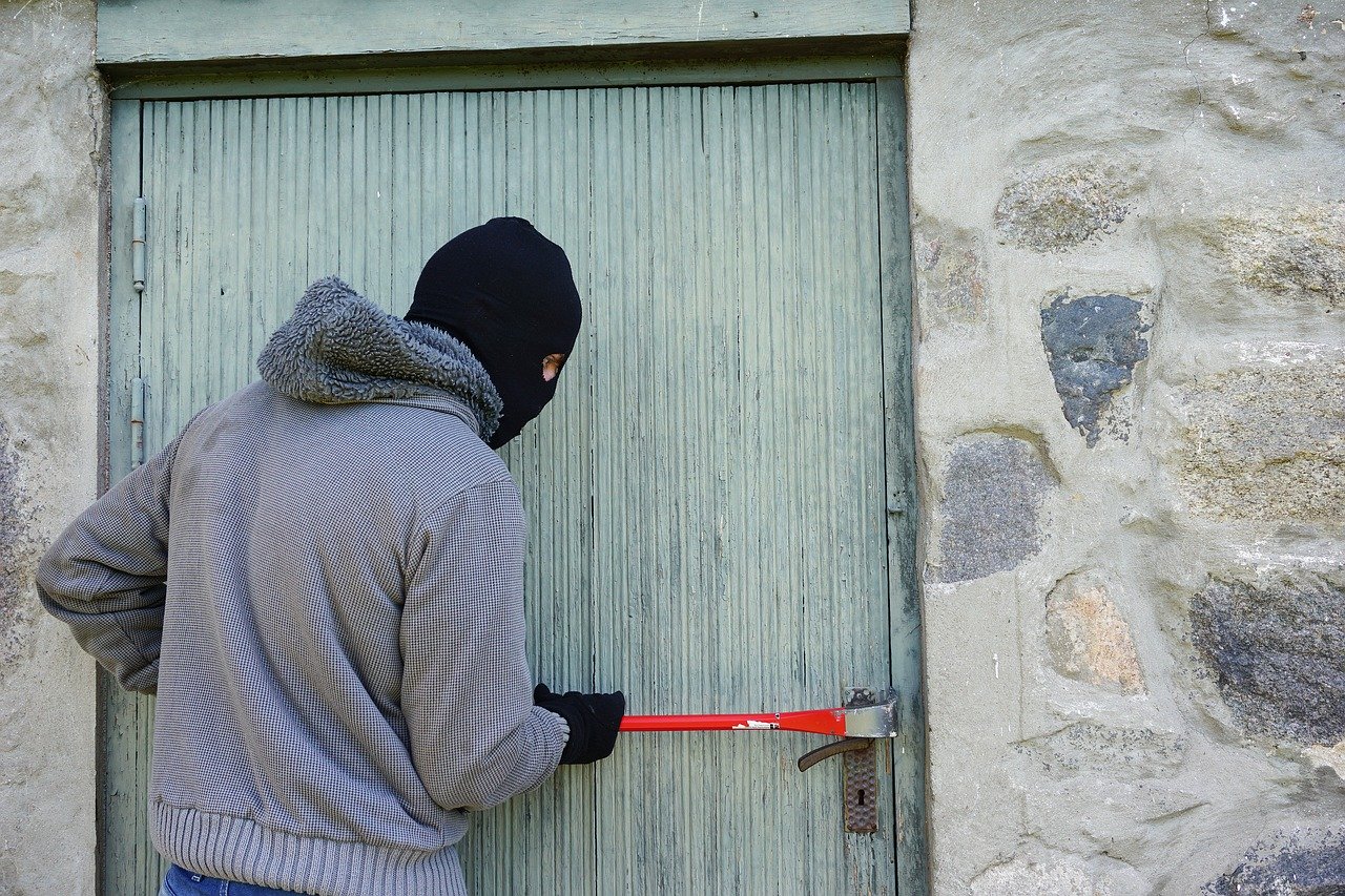 A burglar breaking into a house with a crowbar