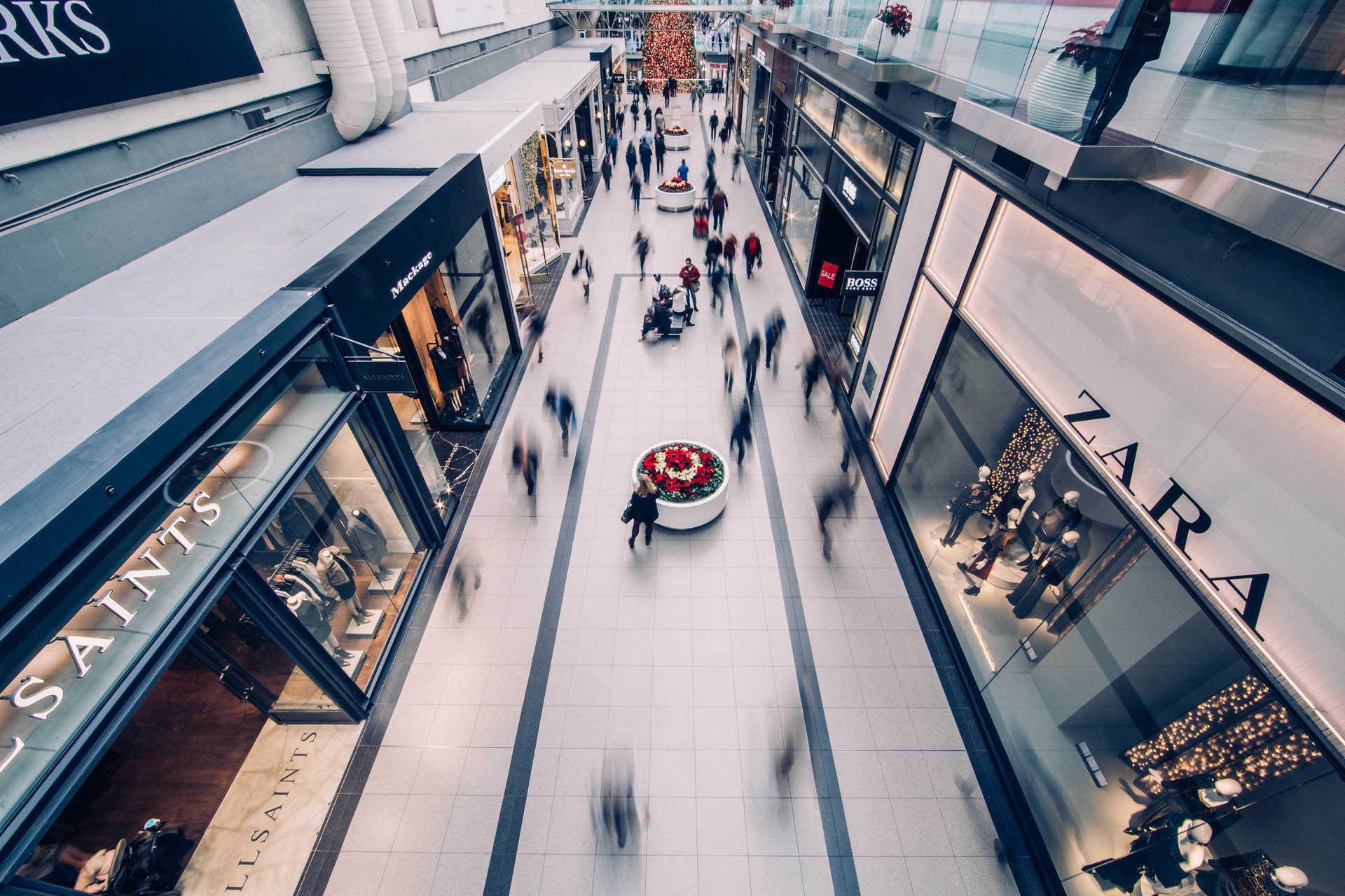 A mall walkway with blurs of people walking past storefronts