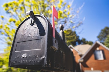 A block U.S. mailbox with a red mail flag in the upward position