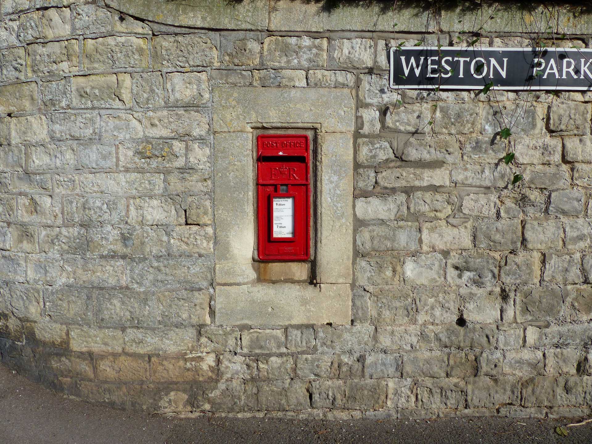 A red english mailbox below a sign that reads "Weston Park"