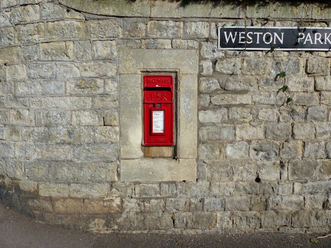 A red english mailbox below a sign that reads "Weston Park"