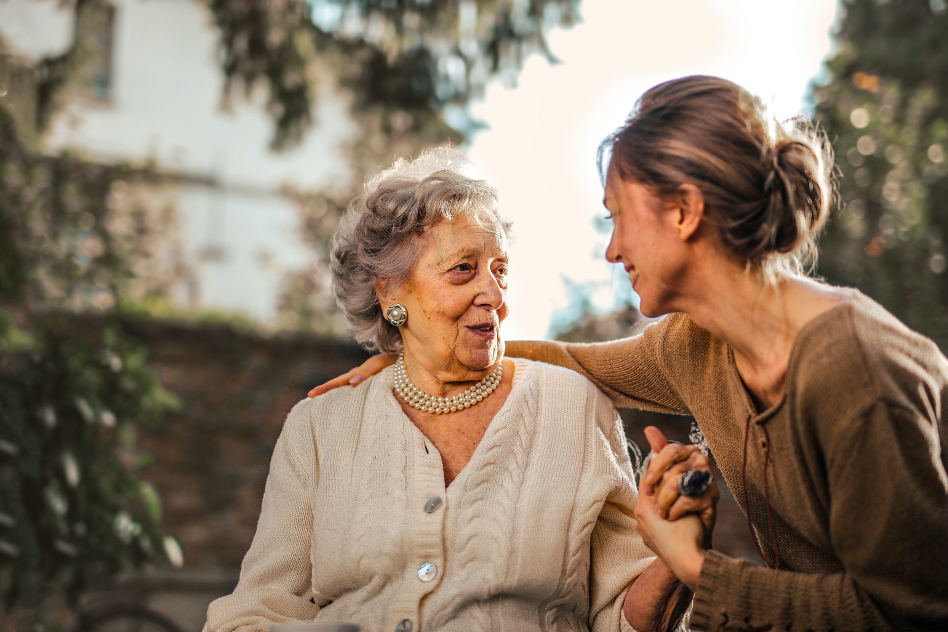 An elderly woman and young woman holding hands and smiling