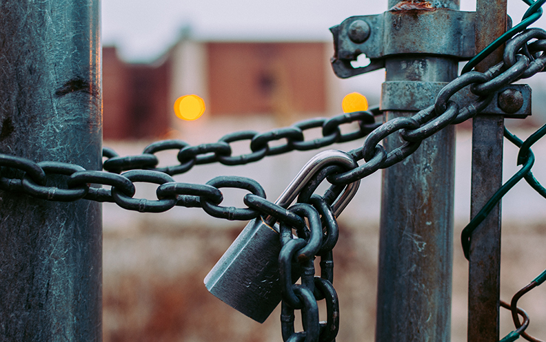 a Metal gate tied shut with a chain and padlock.