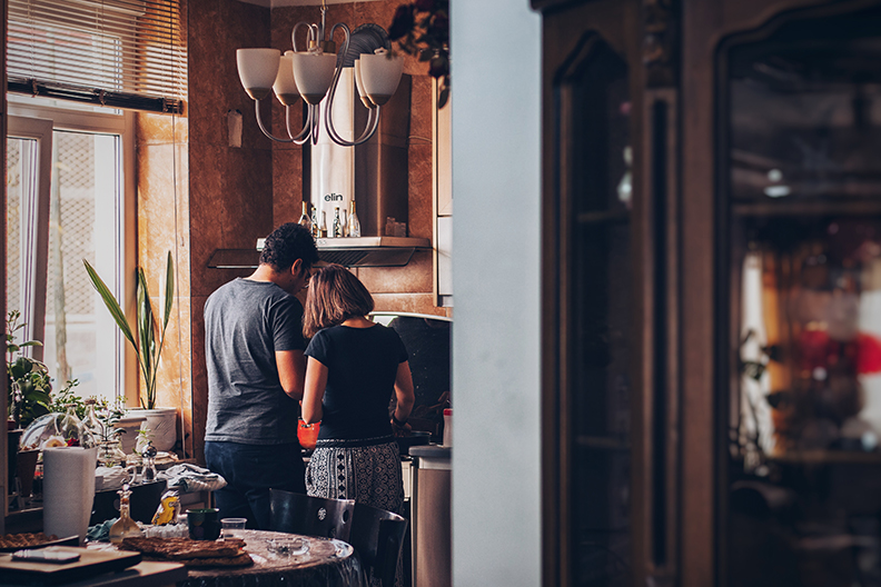 A couple in their pajamas cooking a meal in their cozy kitchen.