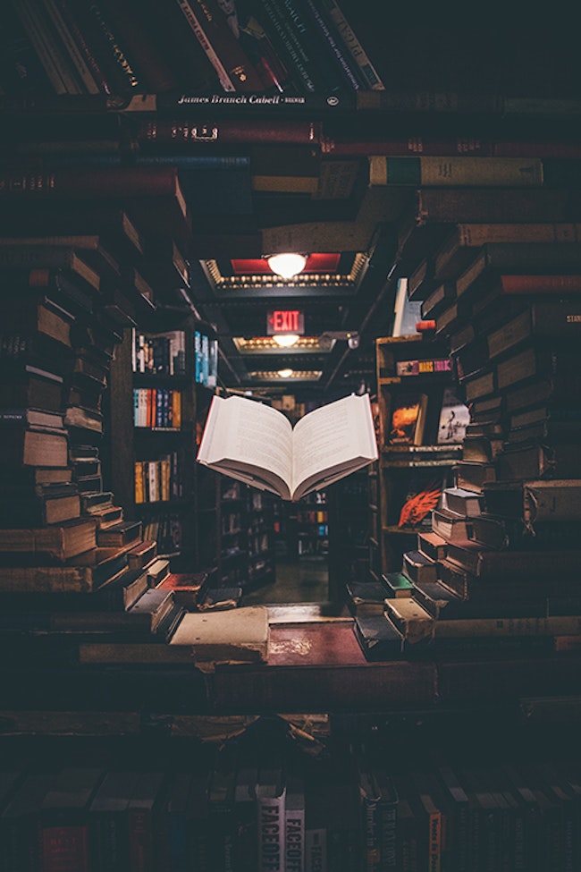 An open book is suspended in a circular arch within a book store.