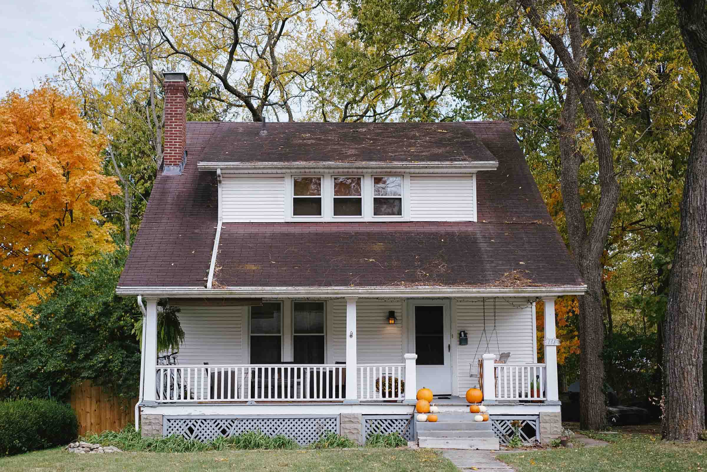 White New England style house with colorful trees in the background.