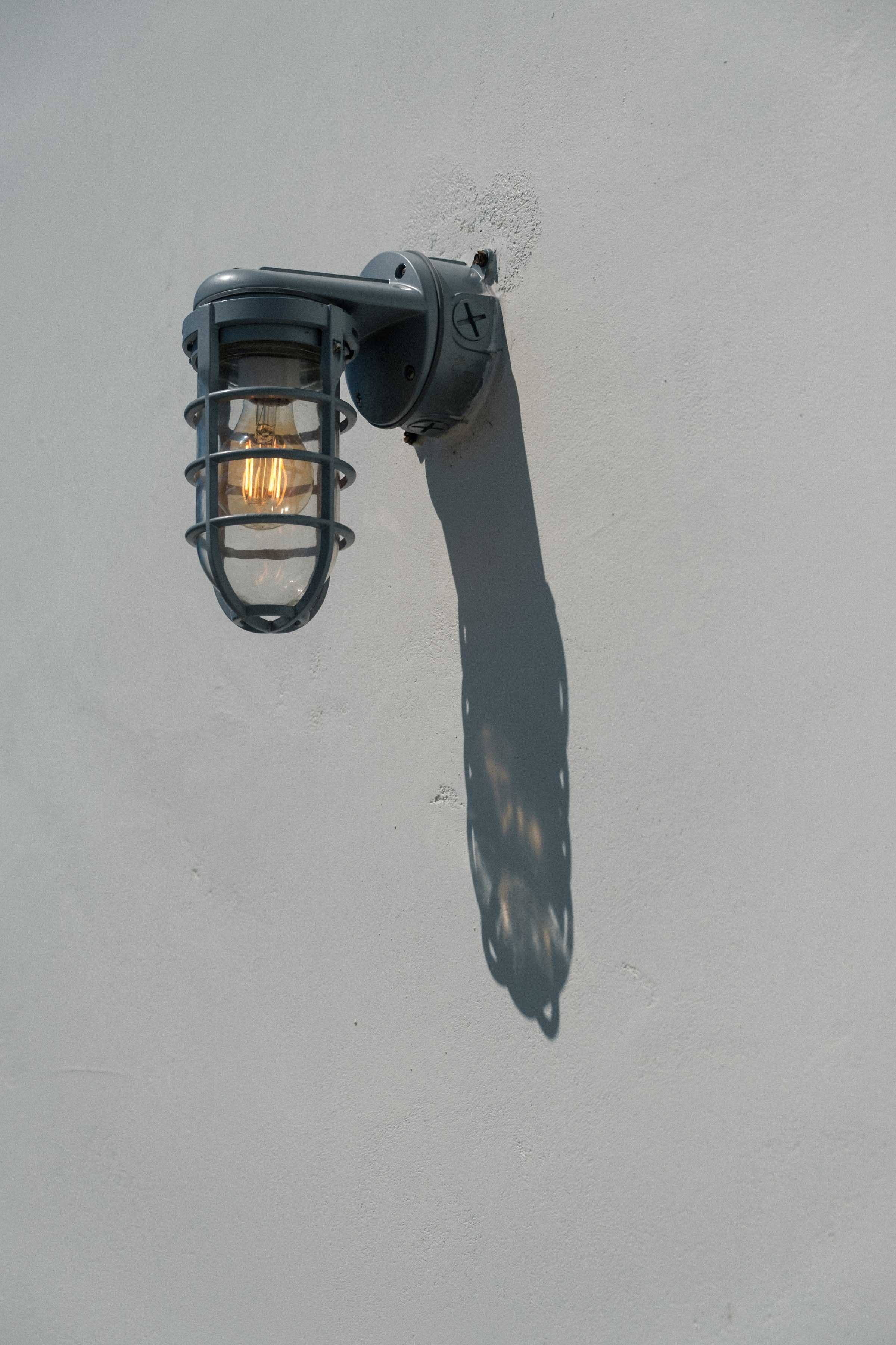 An exterior lamp on a white concrete wall