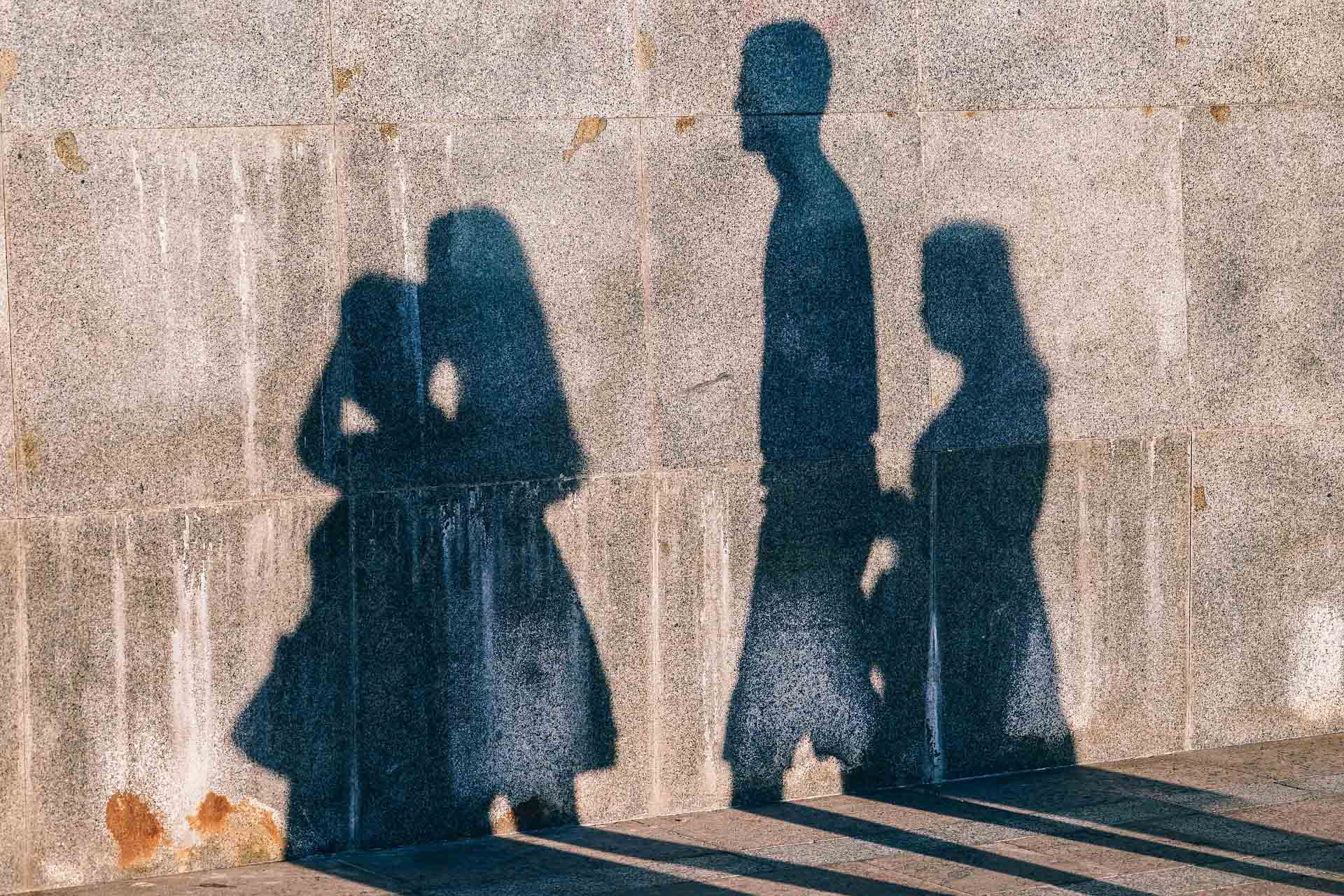 Shadows of four people on a concrete wall.