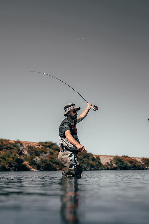 Fisherman standing in thigh high water casting his line.