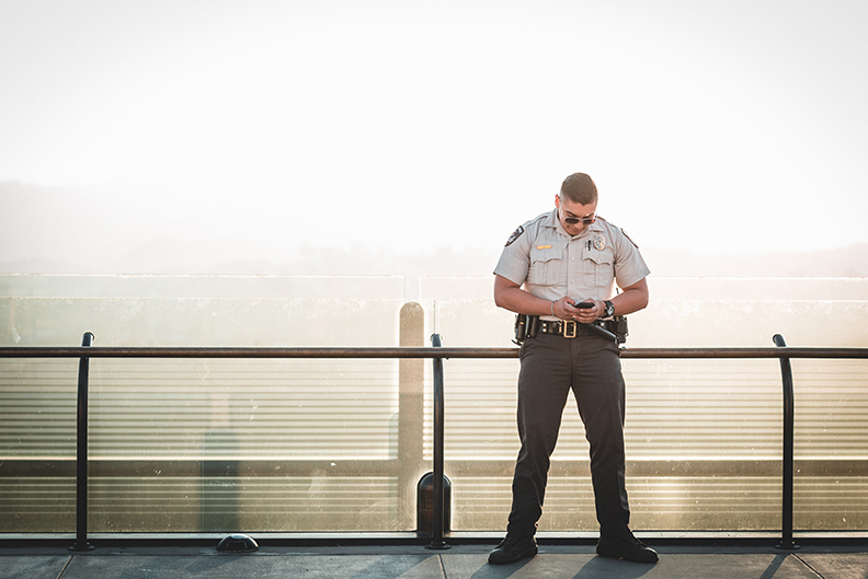 One of the personal security guards checking their phone on top of a skyscraper.