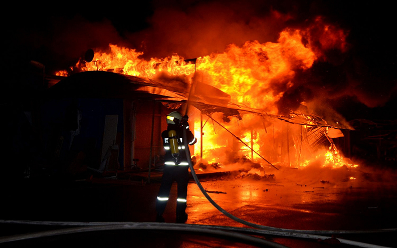 Firefighter Hosing Down Burning House that did not have a diy home fire sprinkler system