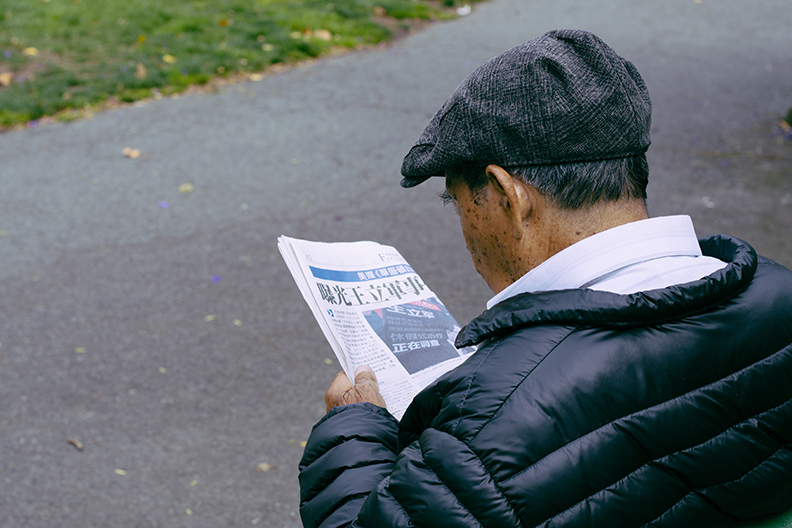 A man reading a newspaper in the street. 