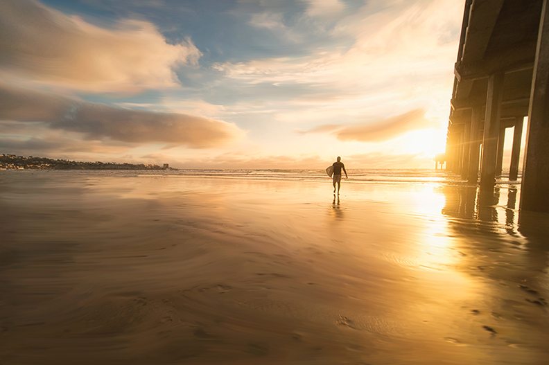Surfer Walking Near Pier in San Diego at Sunset