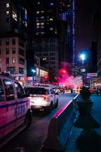 Police Cars on Busy City Corner with lights on.