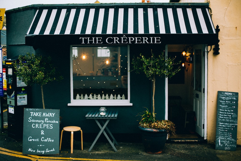 The front of a Creperie with a black and white awning.