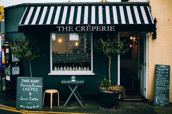 The front of a Creperie with a black and white awning.
