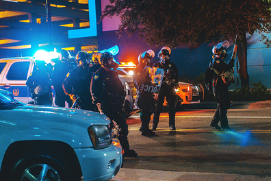 Several police officers forming a perimeter at night.