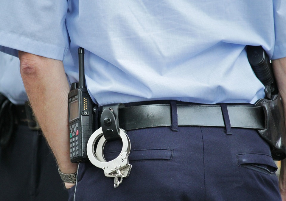 An officer's back with a radio and handcuffs