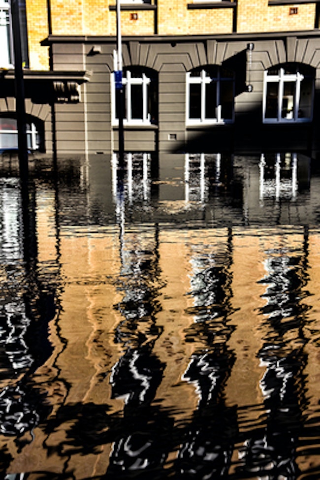 Flooded building due to not having an automatic water shut off valve. The building's reflection is seen in the flood water.
