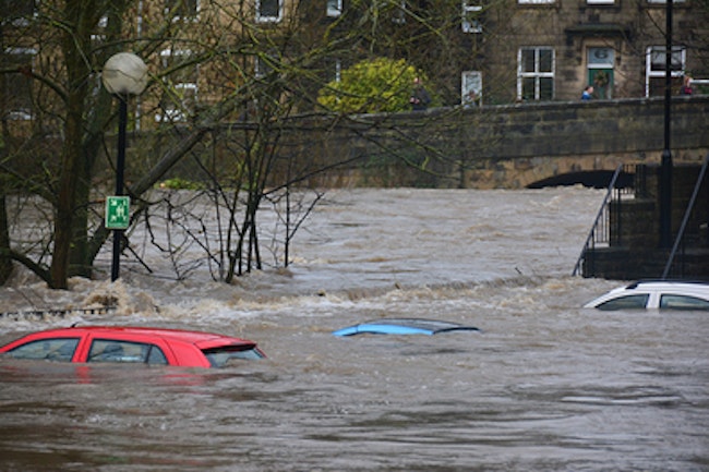 several roofs of cars poking out of flood waters in a city
