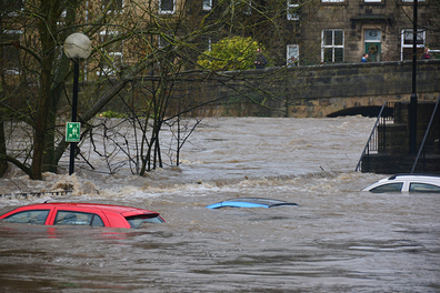 Only the roofs of cars can be seen above the dirty flood of water.