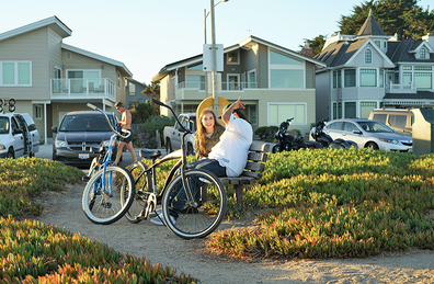 Neighbors with bikes sit and chat in front of their houses.