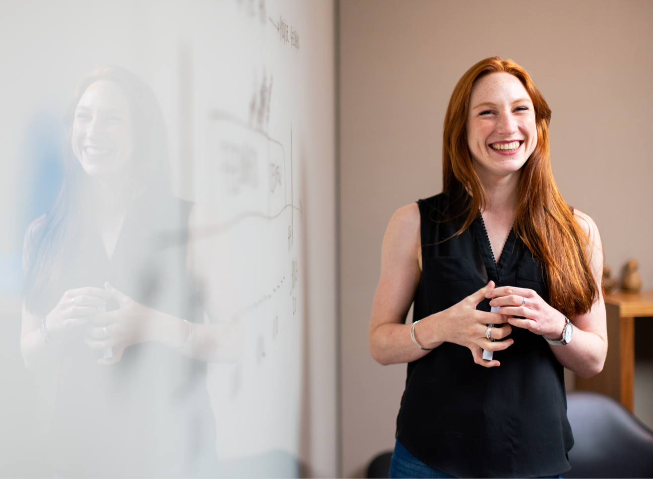 Red headed teacher smiling at the white board.