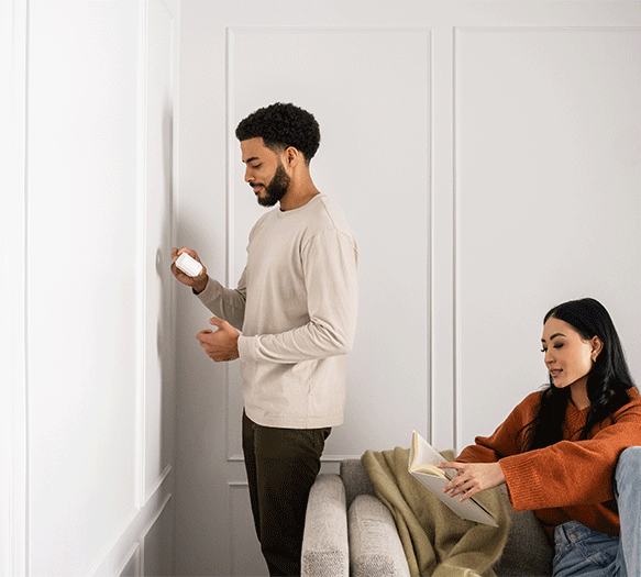 man installing motion detector with woman