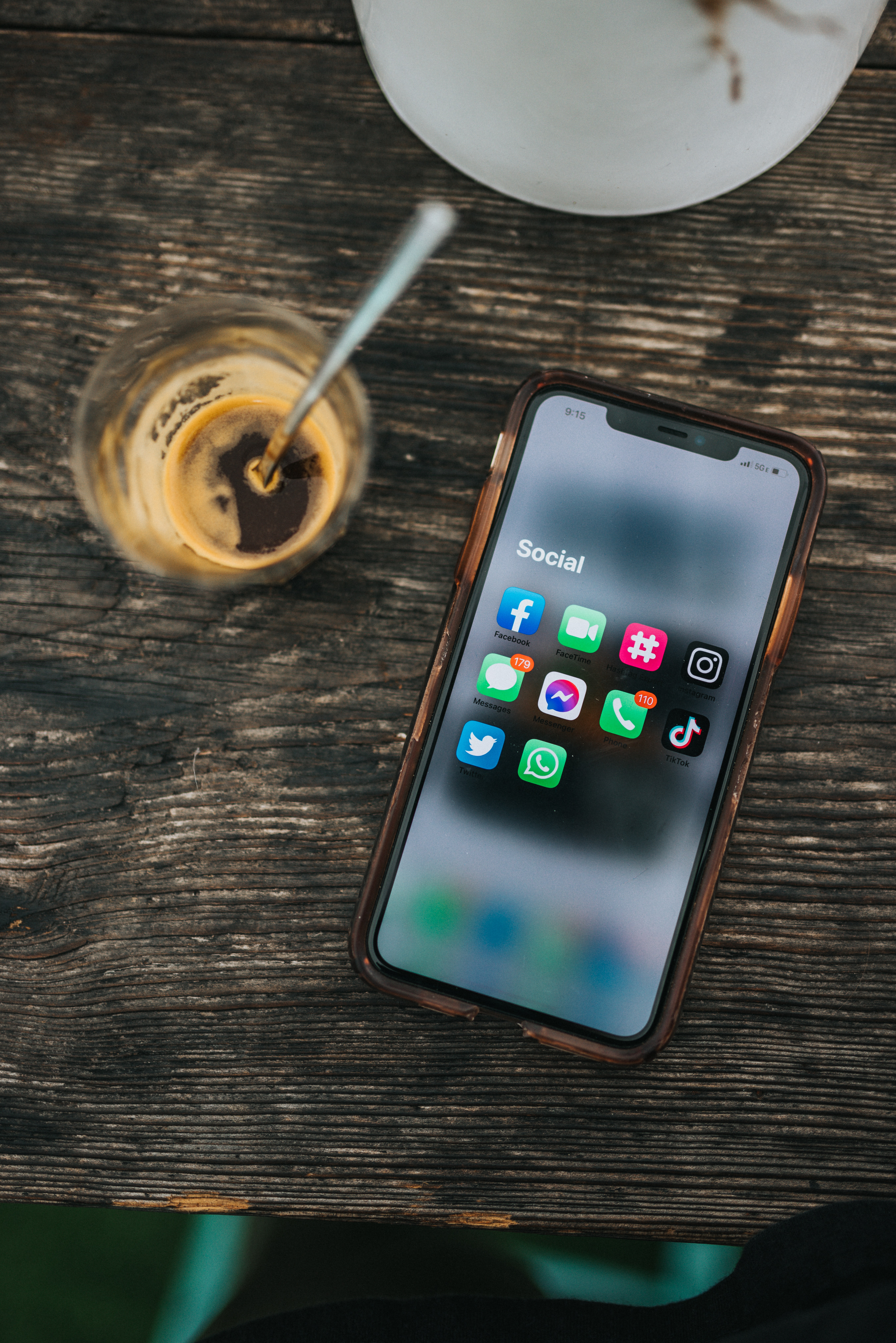 Smart phone with apps showing on screen set on a table next to coffee.