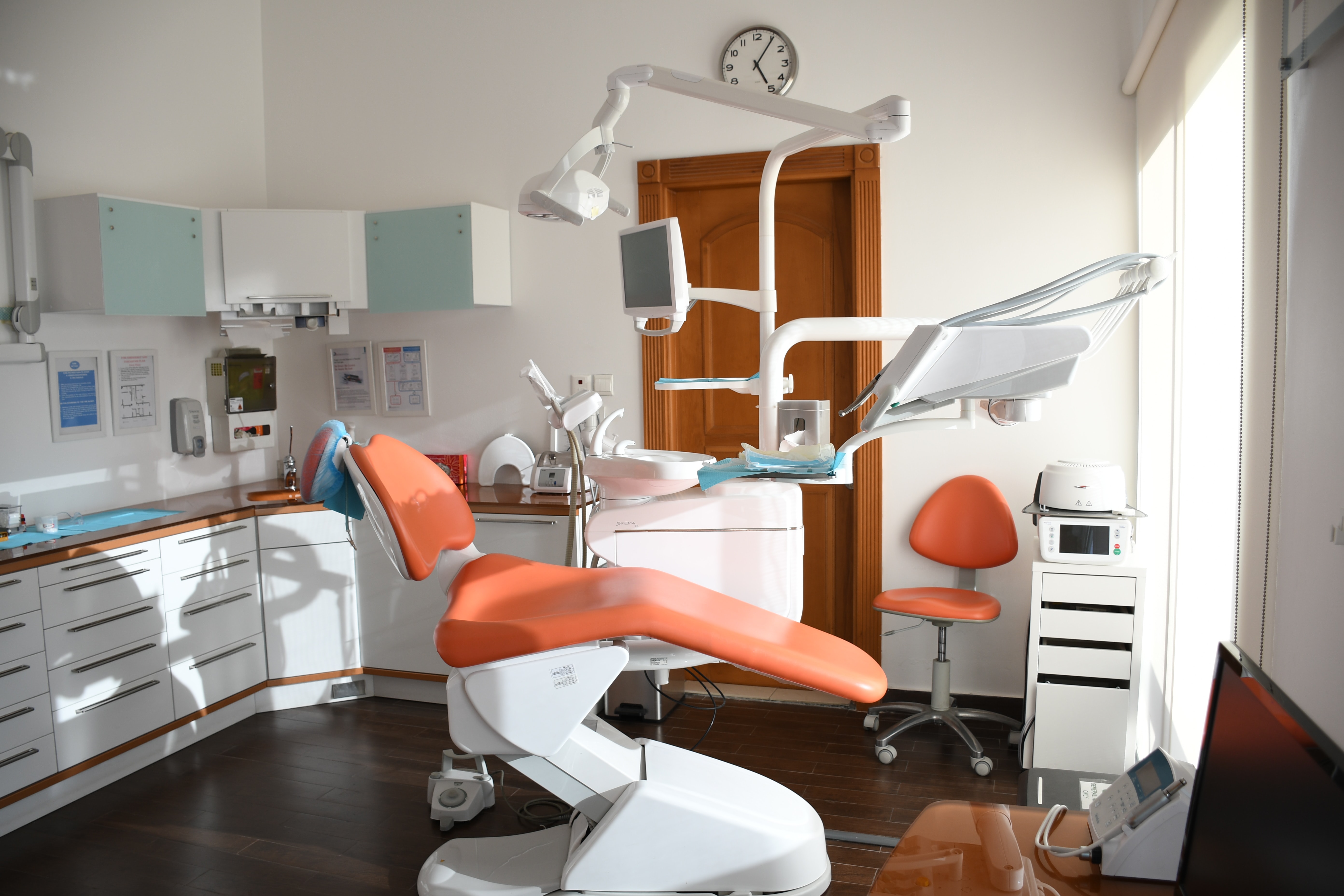 Reclined orange dentist chair in a dental office.