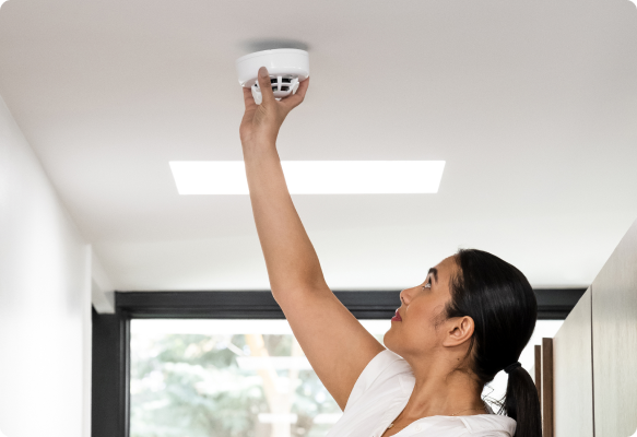 Woman installing smoke detector