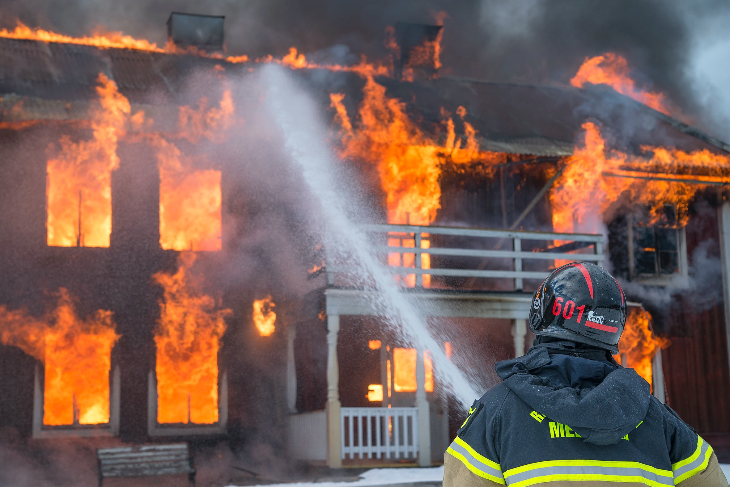 A fire fighter uses a water hose to battle a house fire.