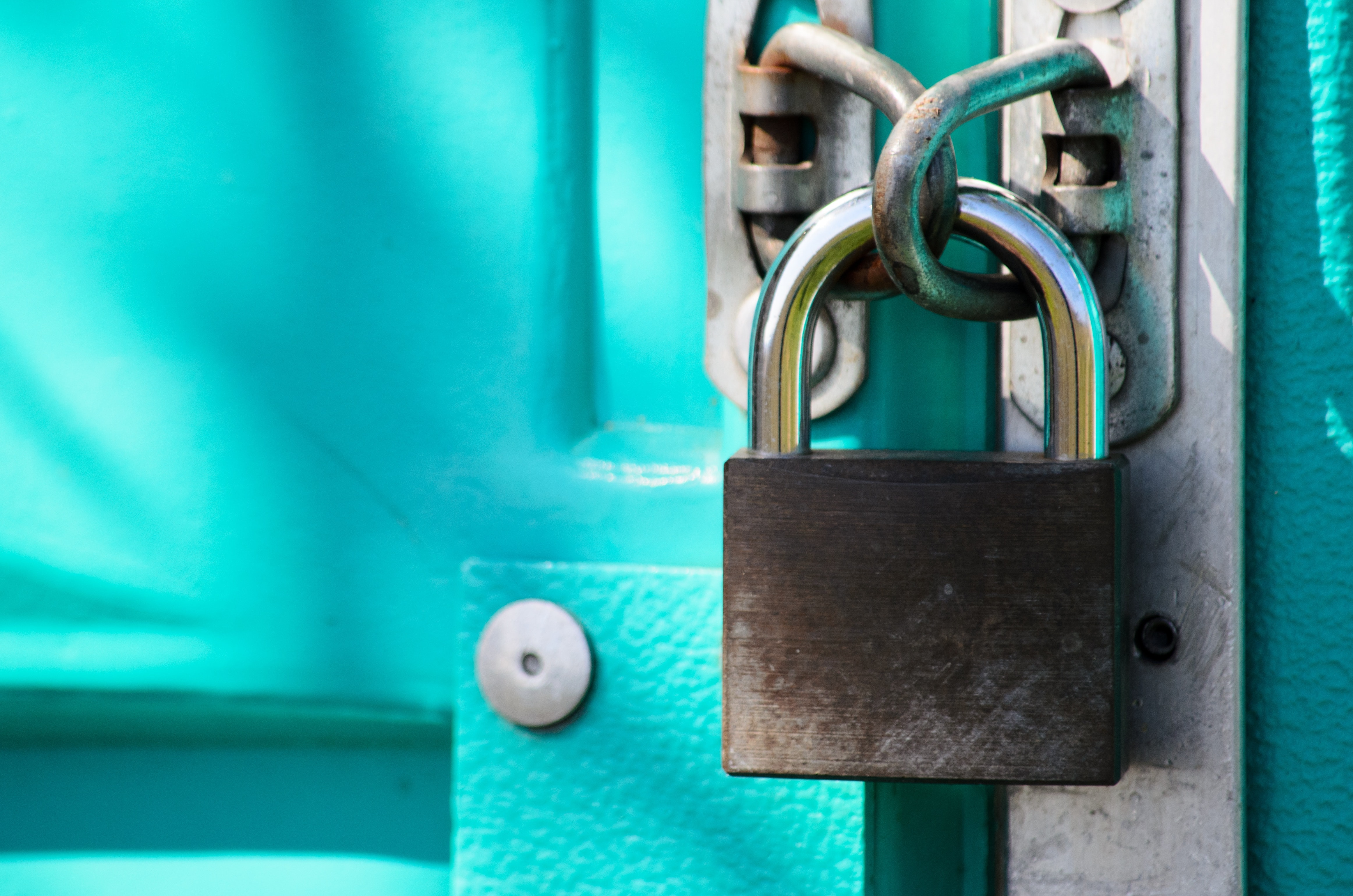 Padlock on a teal door or gate.