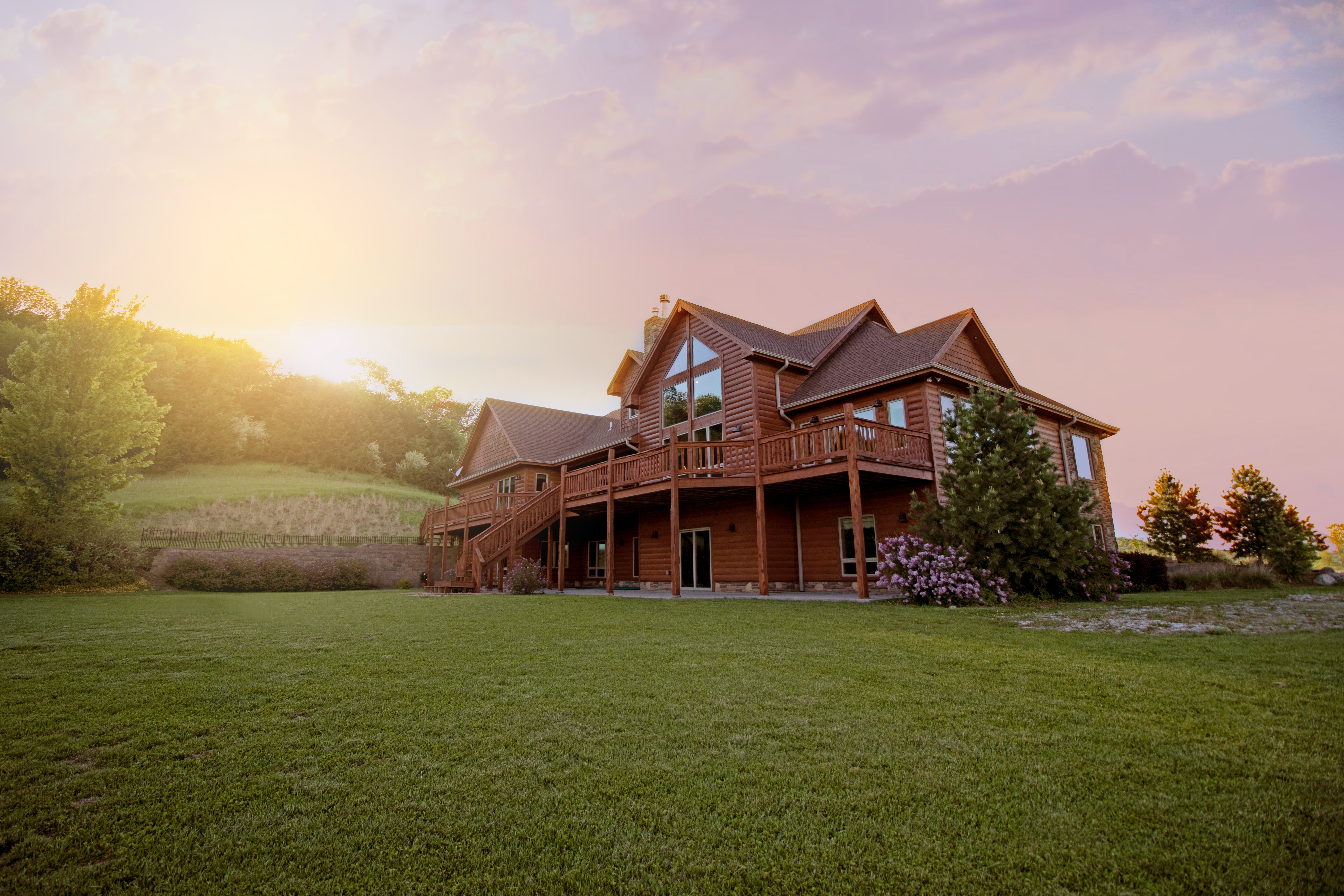 Two-story home with lots of grass at sunset.