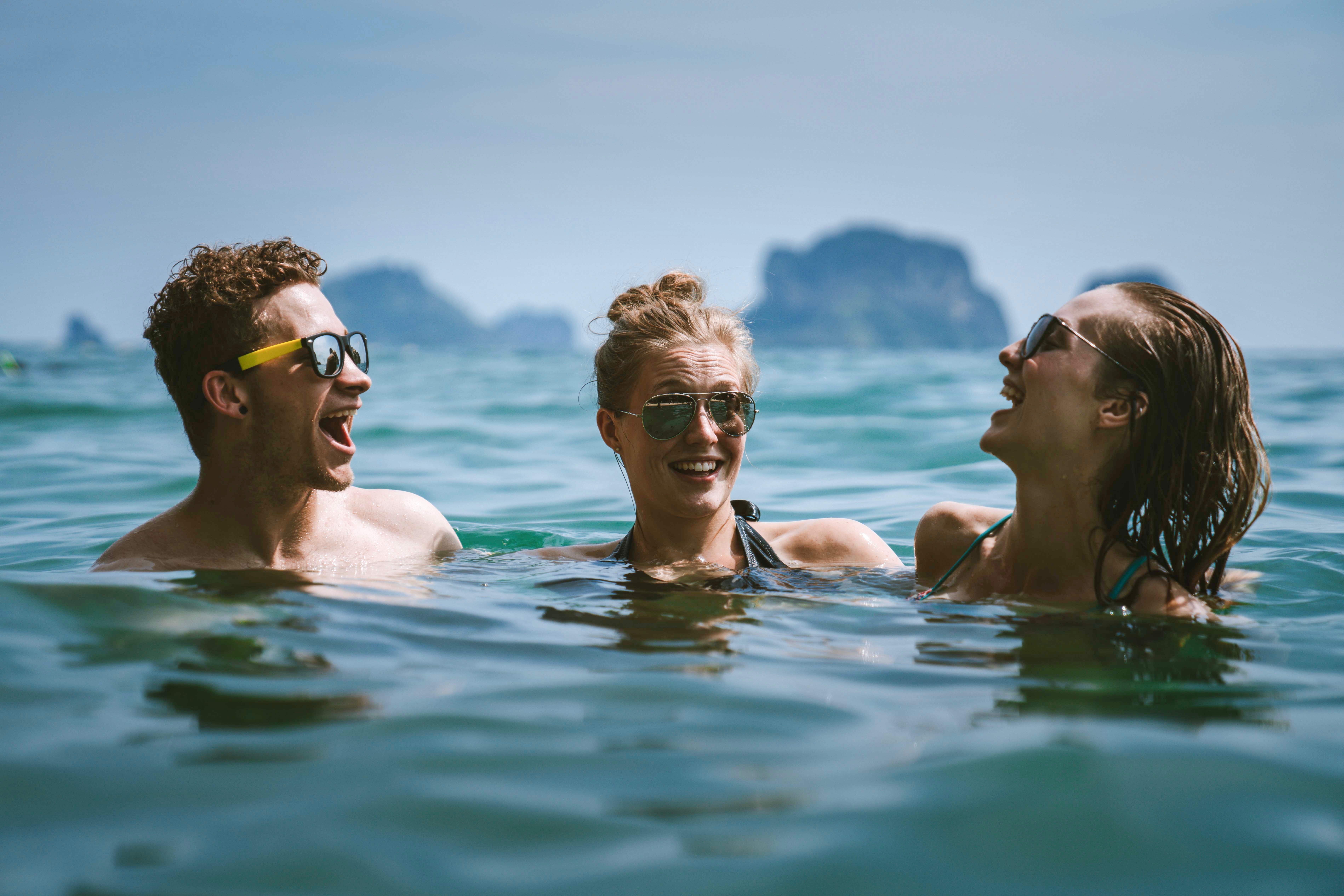 Three young adults having fun swimming in a lake.