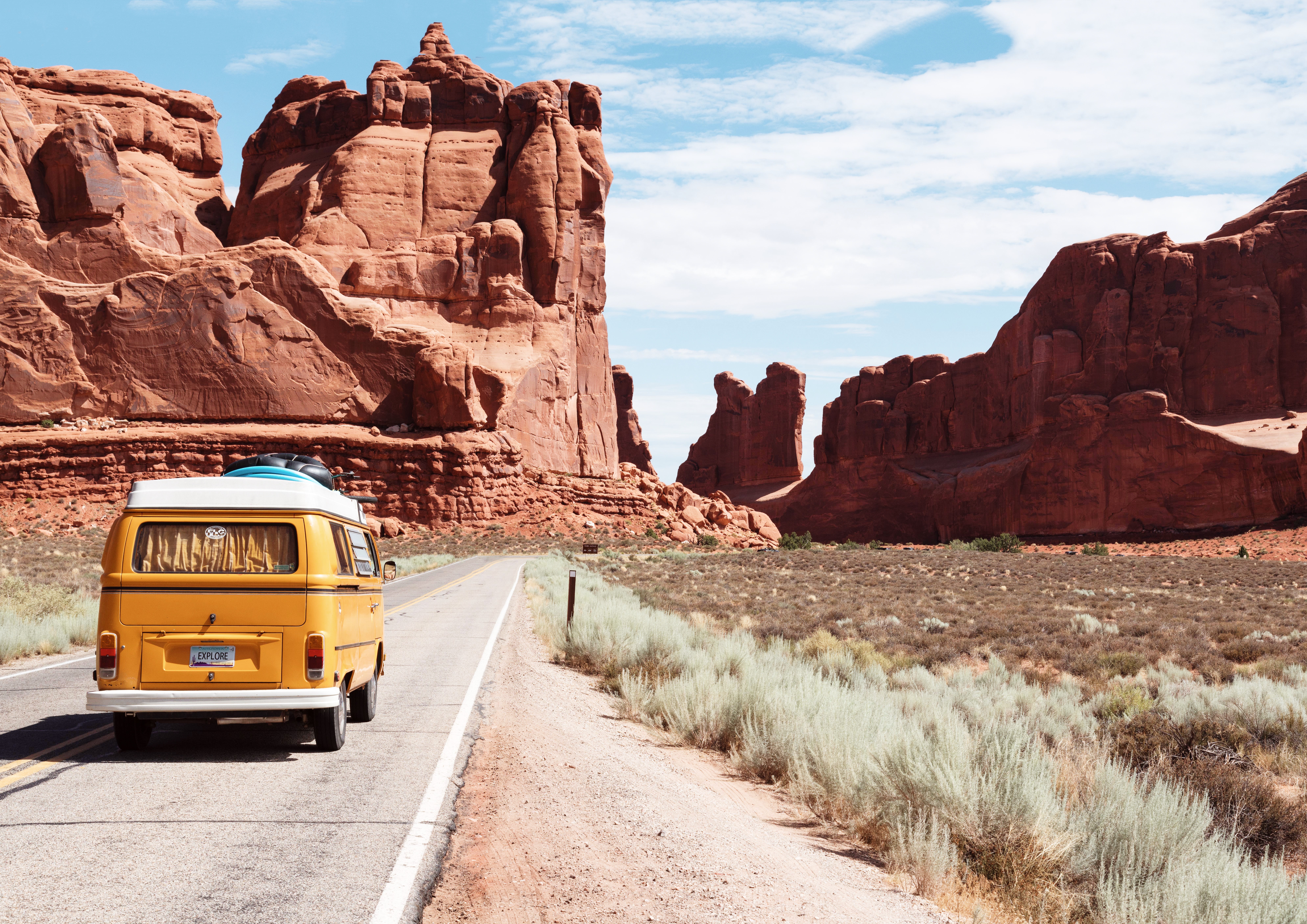 Road trip to the southwest US with red rocks driving a mustard yellow VW van.