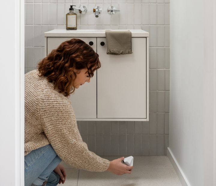 woman installing flood sensor