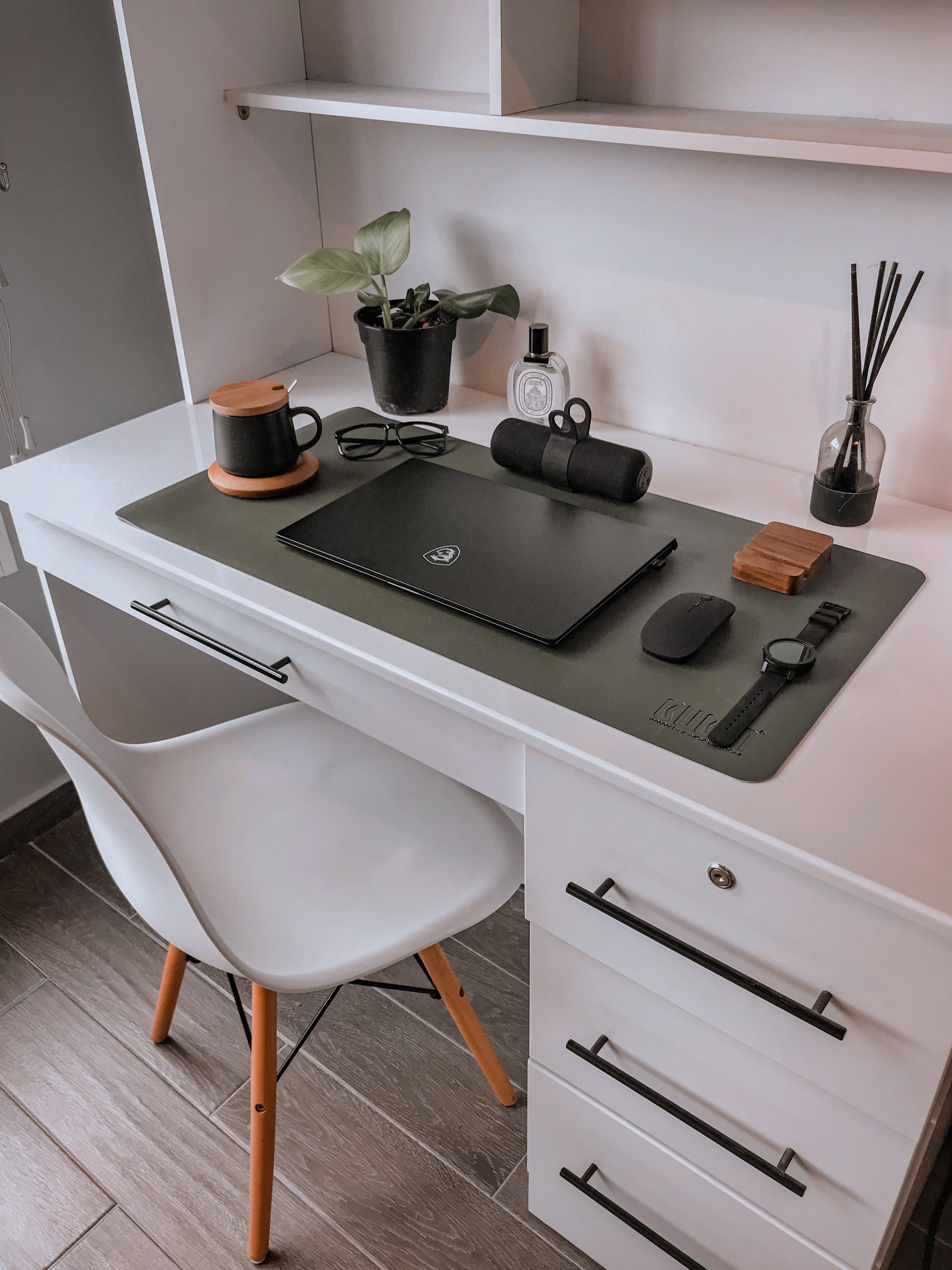 White desk with laptop and supplies on top and three drawers including a lock on the side.