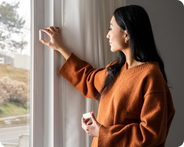 Woman installing a window sensor as part of her Cove home security system.