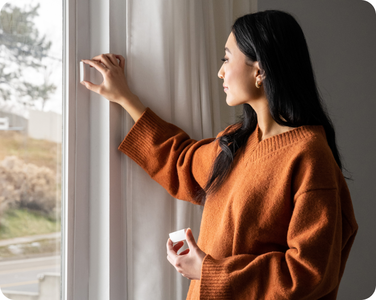 Woman installing a Cove window sensor.