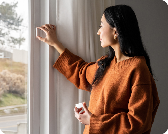 Woman installing a Cove window sensor.