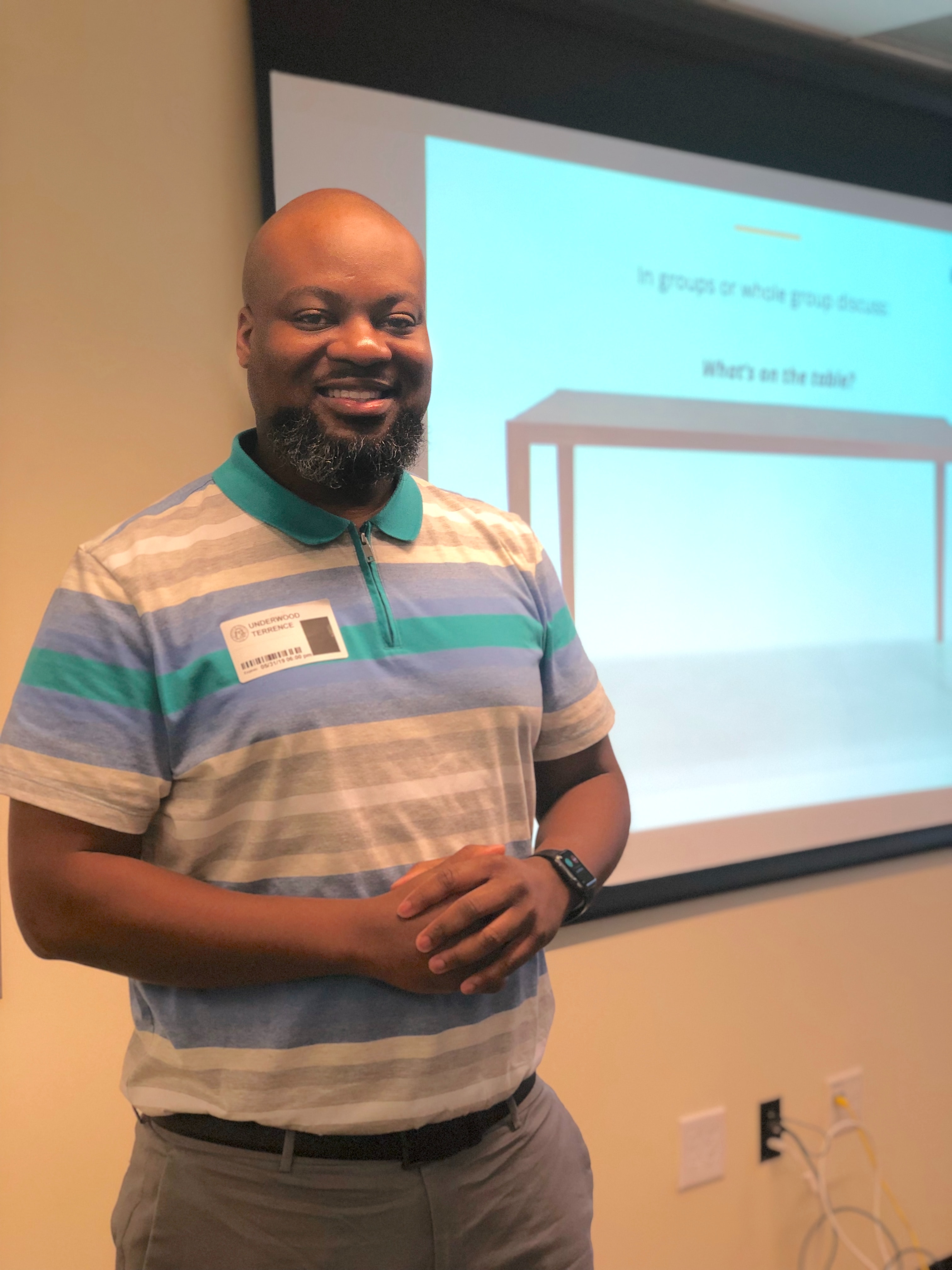 Male teacher standing in front of a projector screen.