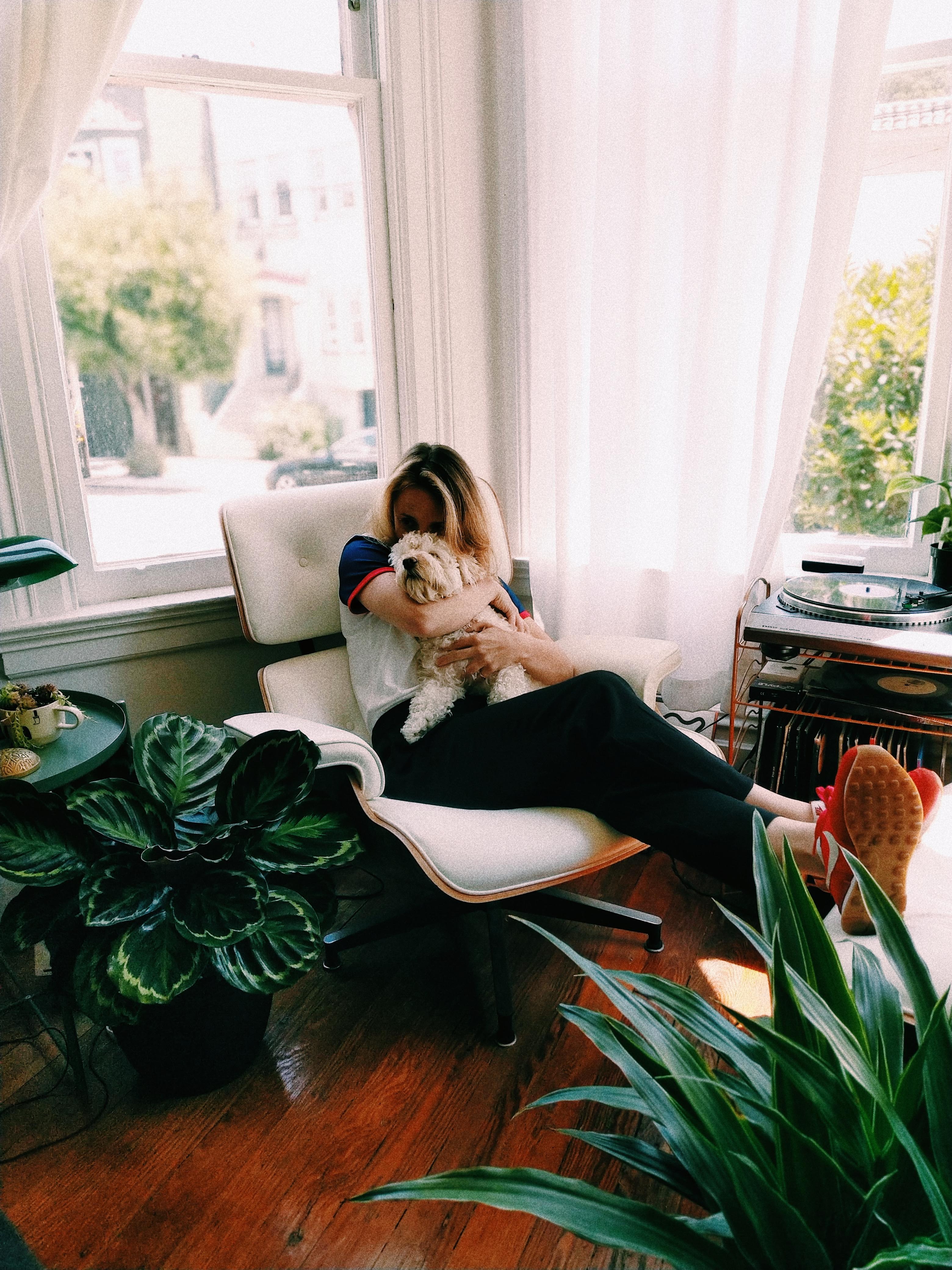 Woman sitting at home cuddling her dog.