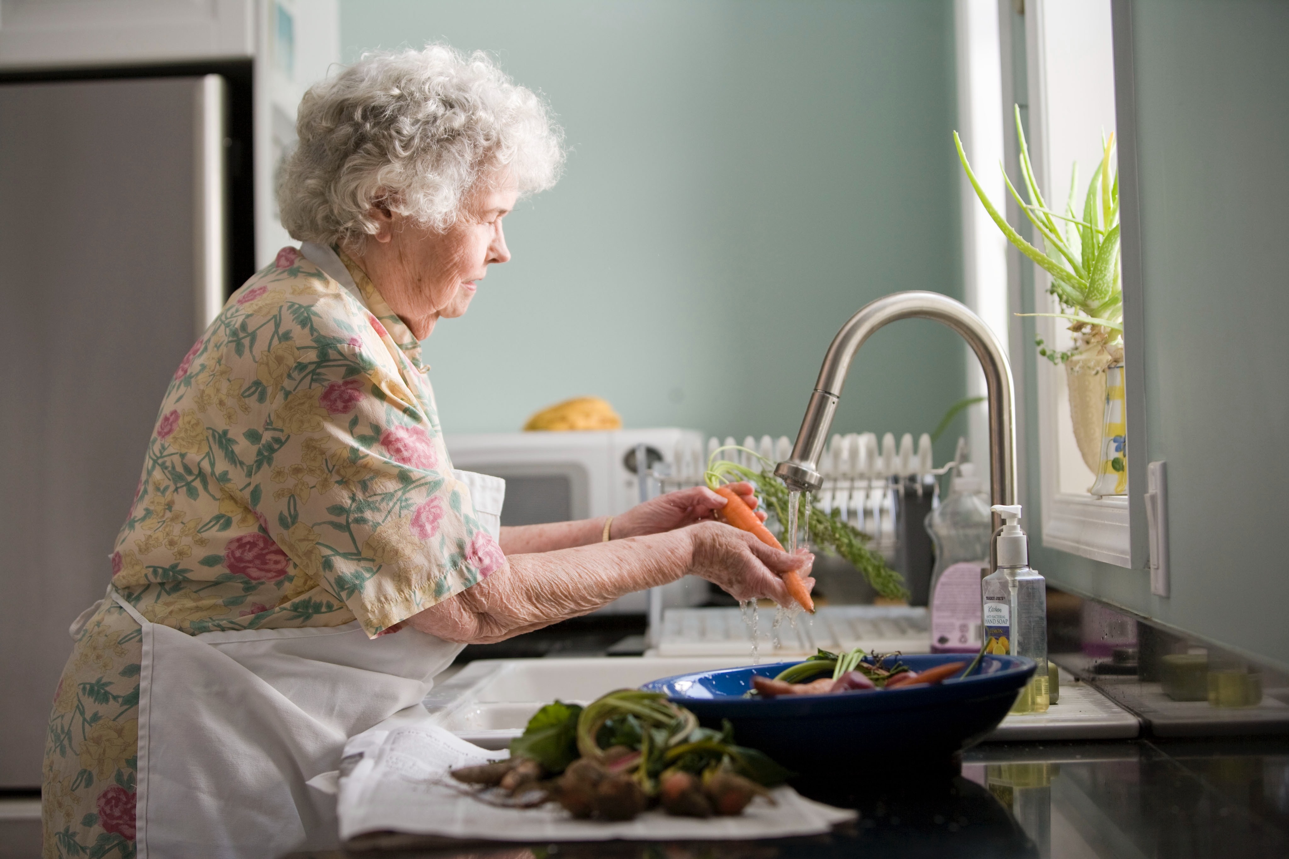 Grandma at home washing vegetables in the kitchen.