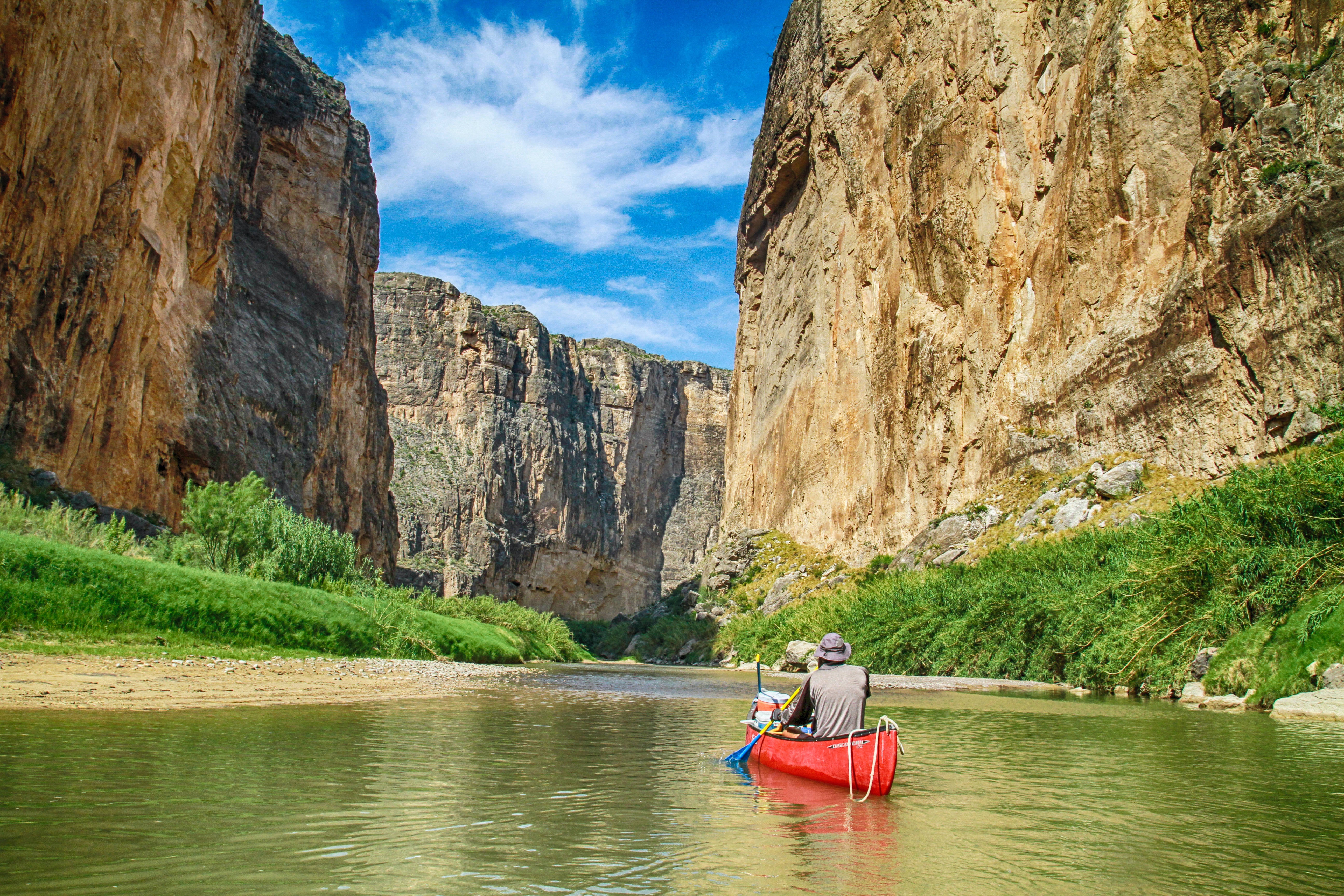 People in a canoe on a river in a canyon ready to go fishing.