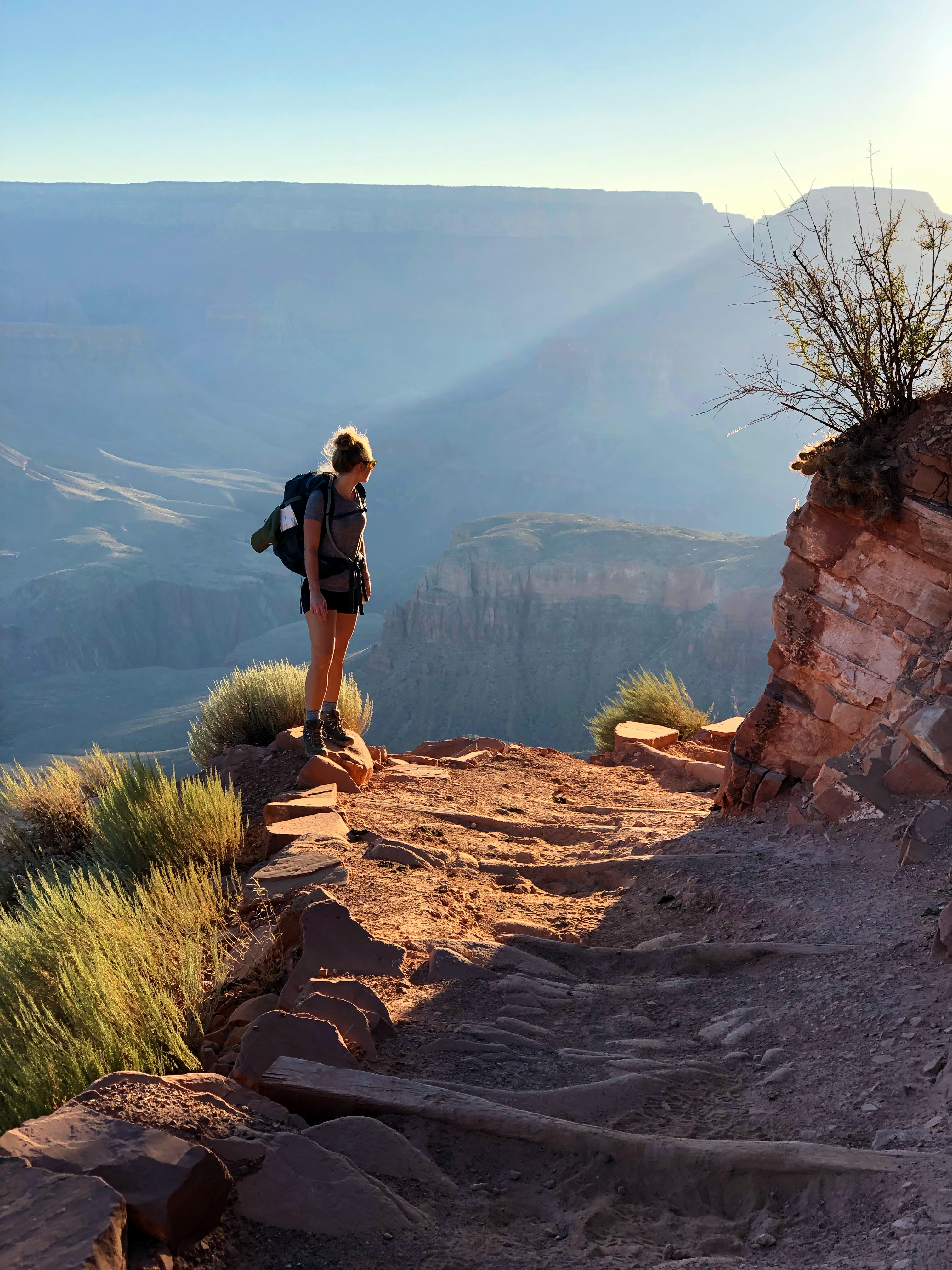Woman with a backpack stopping on the hiking trail admiring the view.