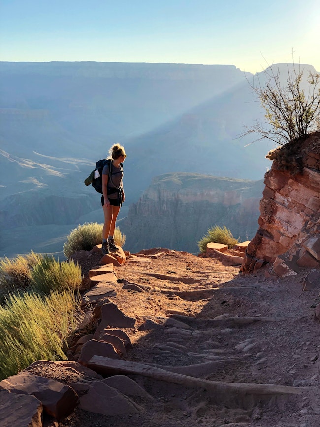 Woman with a backpack stopping on the hiking trail admiring the view.
